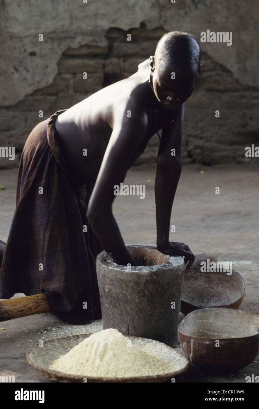 A Dinka woman pounds grains in Thiet feeding camp in Southern Sudan. Stock Photo