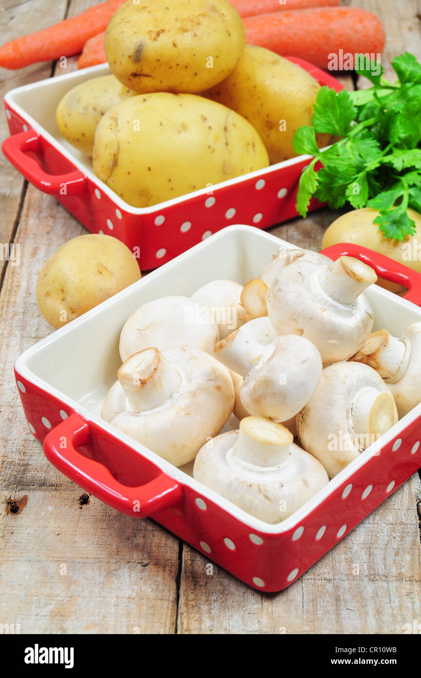 Raw mushrooms and potatoes in red trays Stock Photo