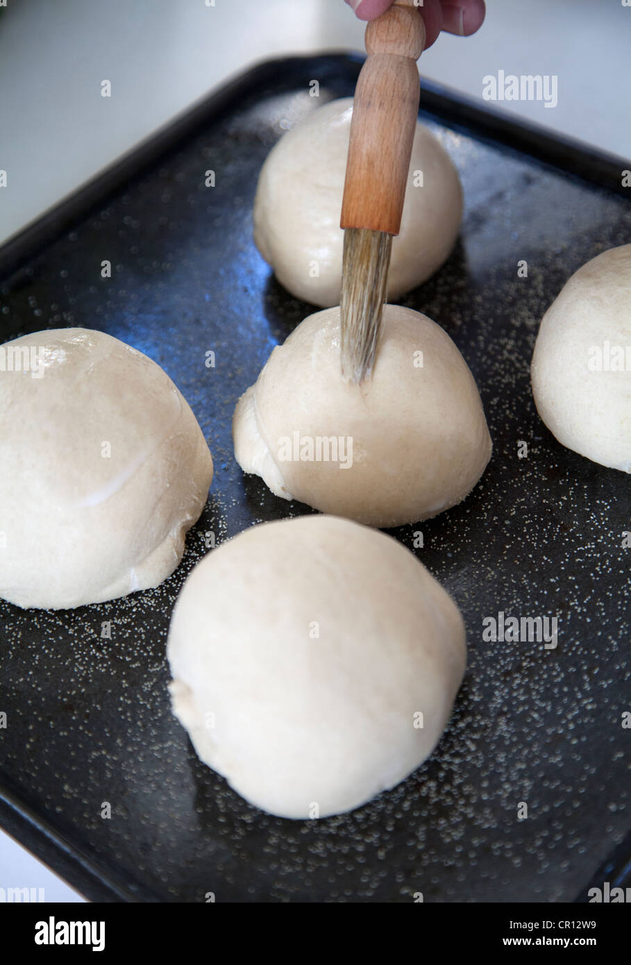 Man Coating Bread dough with milk glaze before baking Stock Photo Alamy