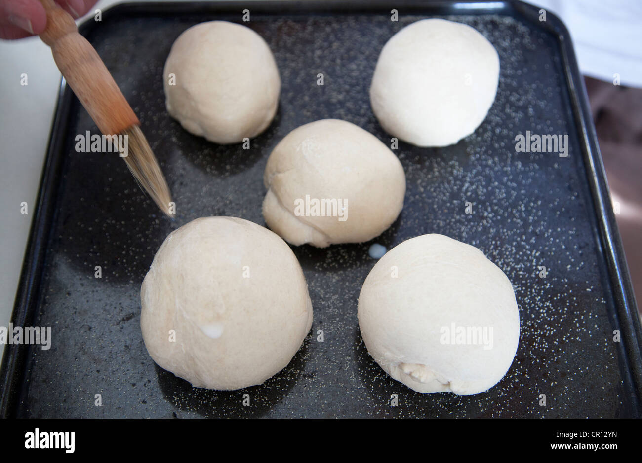 Man Coating Bread dough with milk glaze before baking Stock Photo Alamy