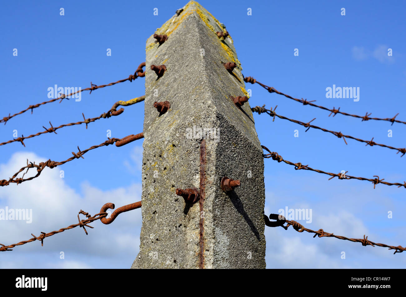old concrete corner post with rusting barbed wire Stock Photo