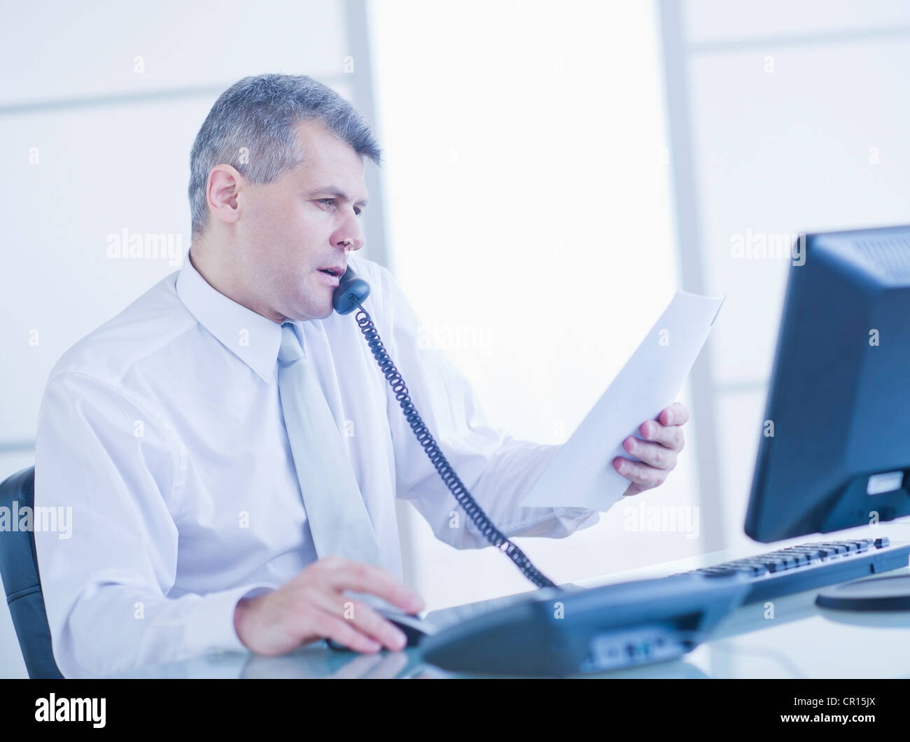 Man sitting in office and talking on landline phone Stock Photo
