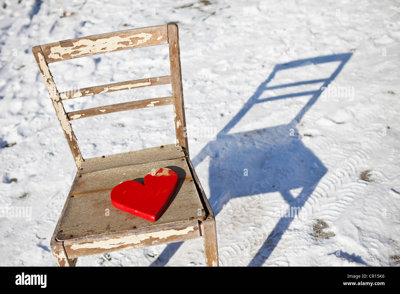 Red wooden heart on an old chair in the snow Stock Photo