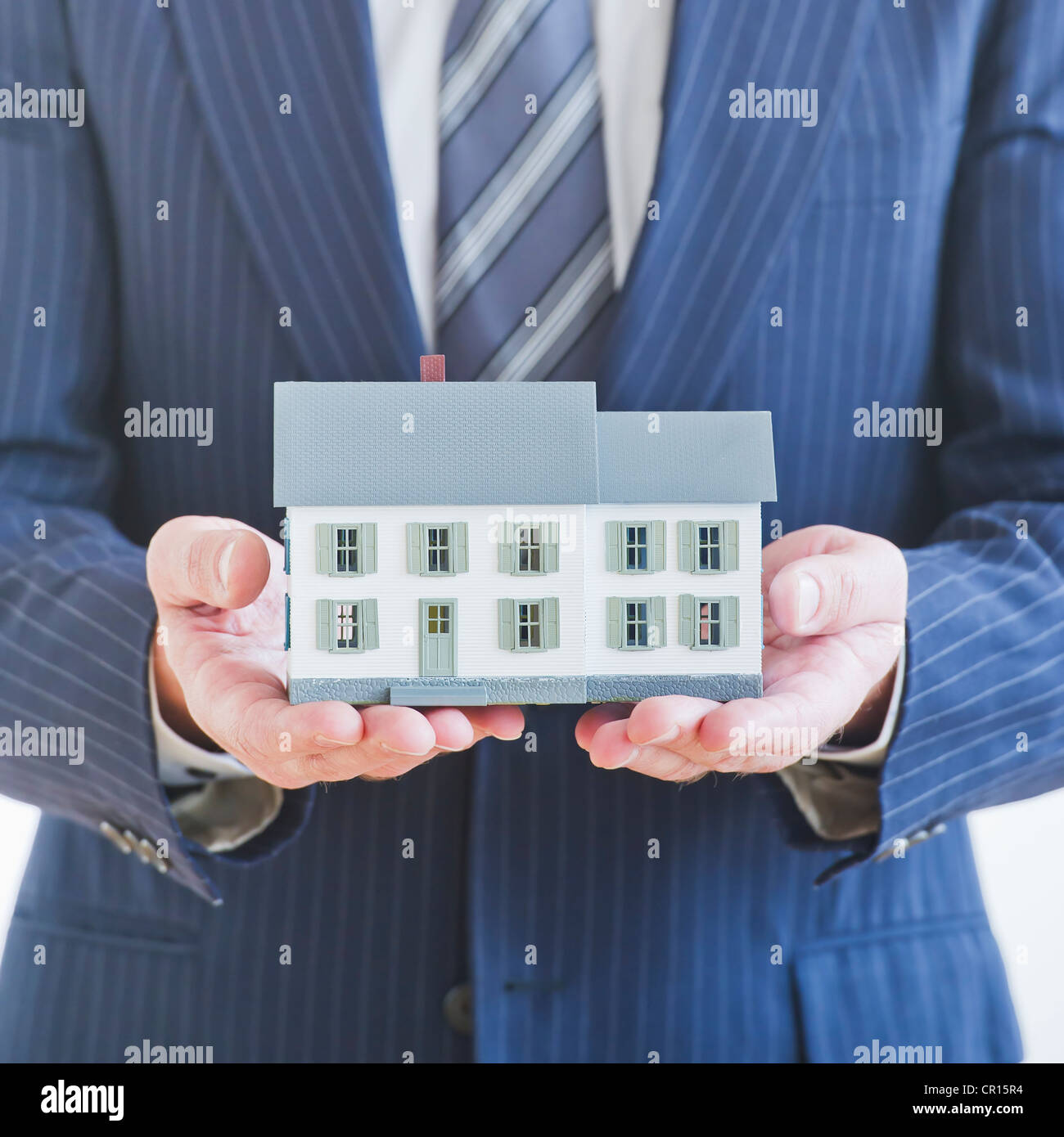 Man wearing suit holding small house model Stock Photo