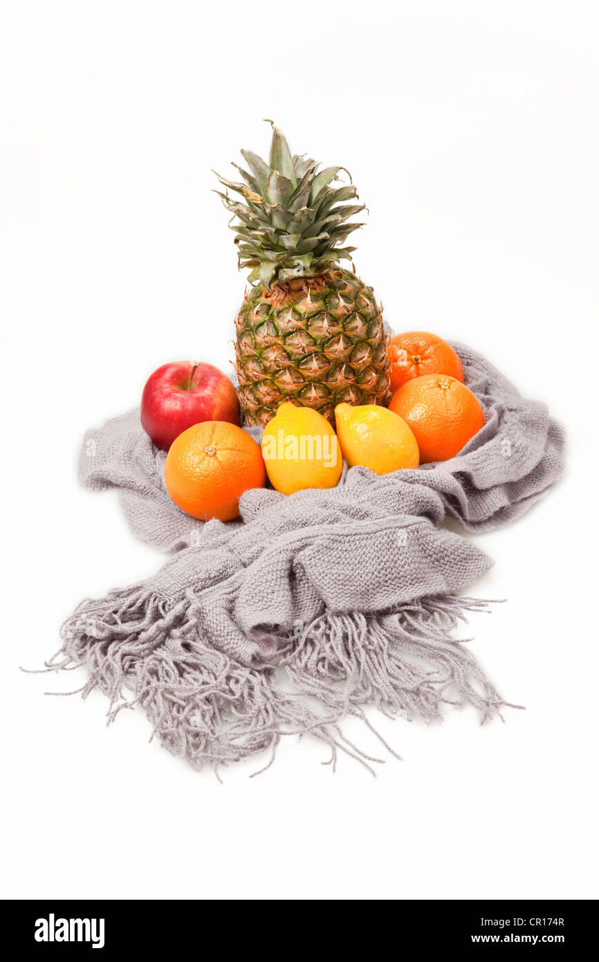 Fruits presented on a scarf, a pineapple, oranges, lemons and an apple Stock Photo