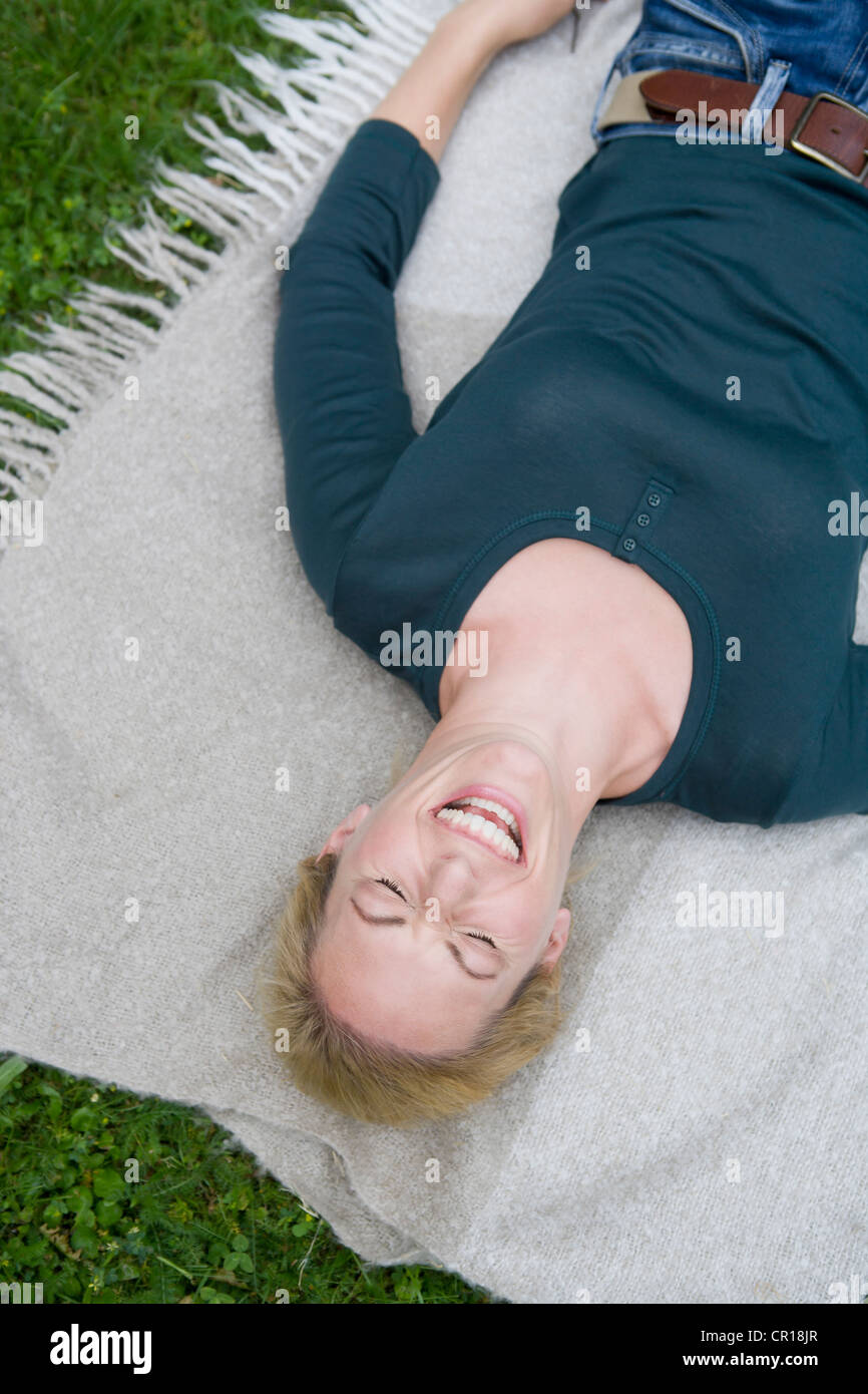 Woman laughing on blanket in grass Stock Photo