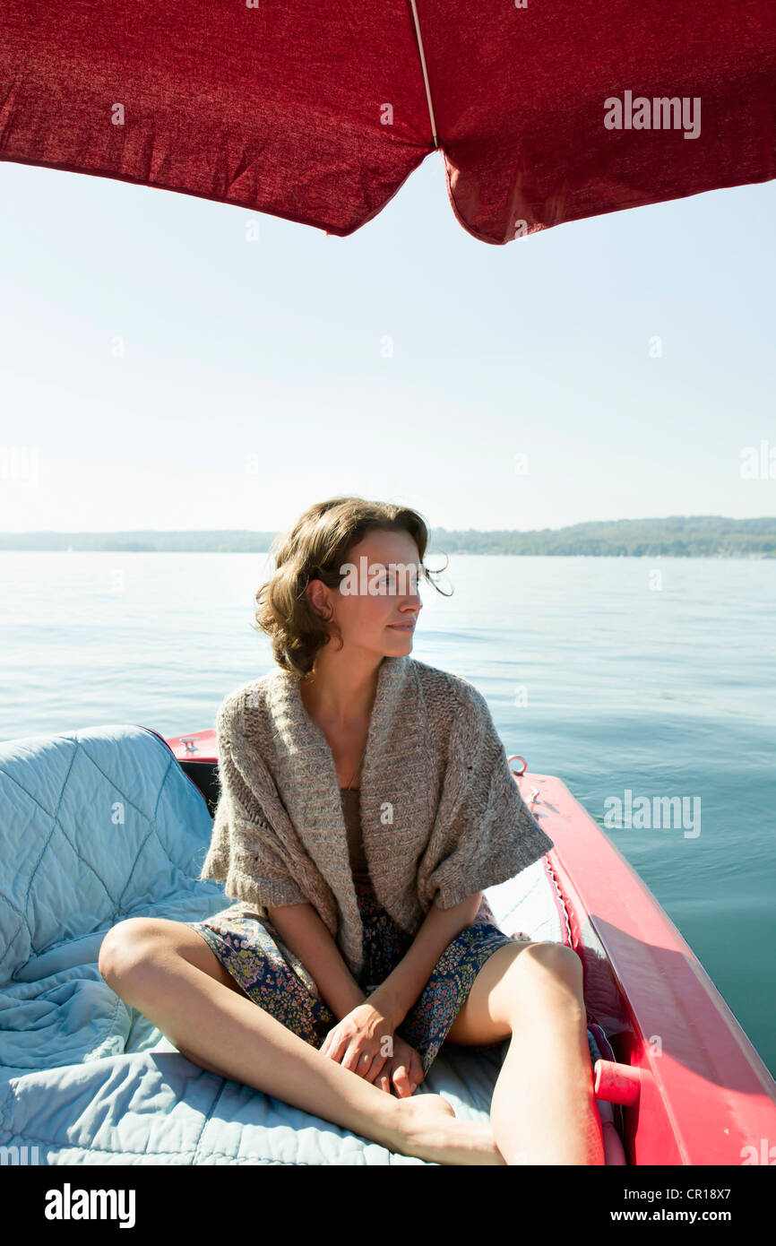 Woman relaxing in boat on still lake Stock Photo