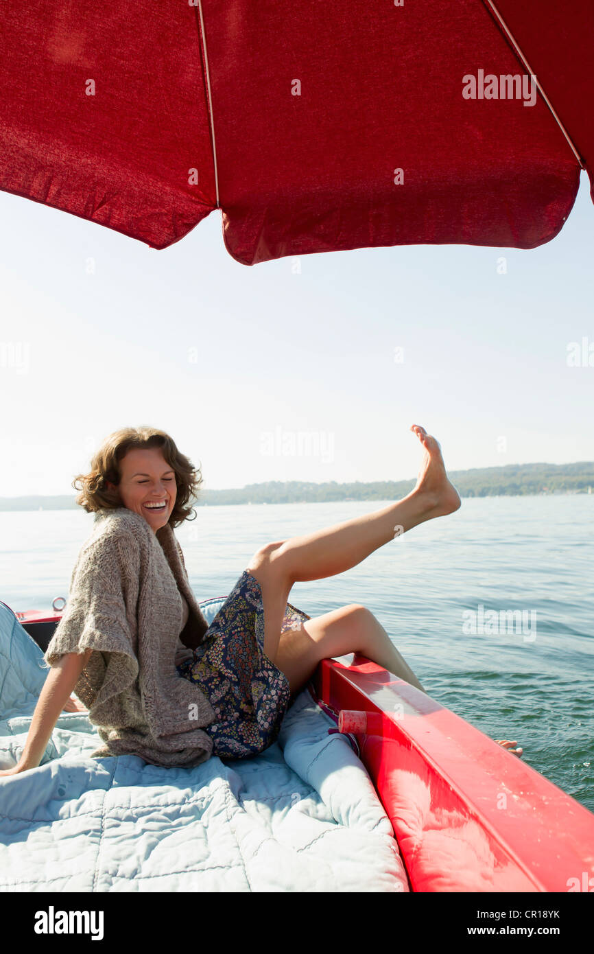 Woman relaxing in boat on still lake Stock Photo