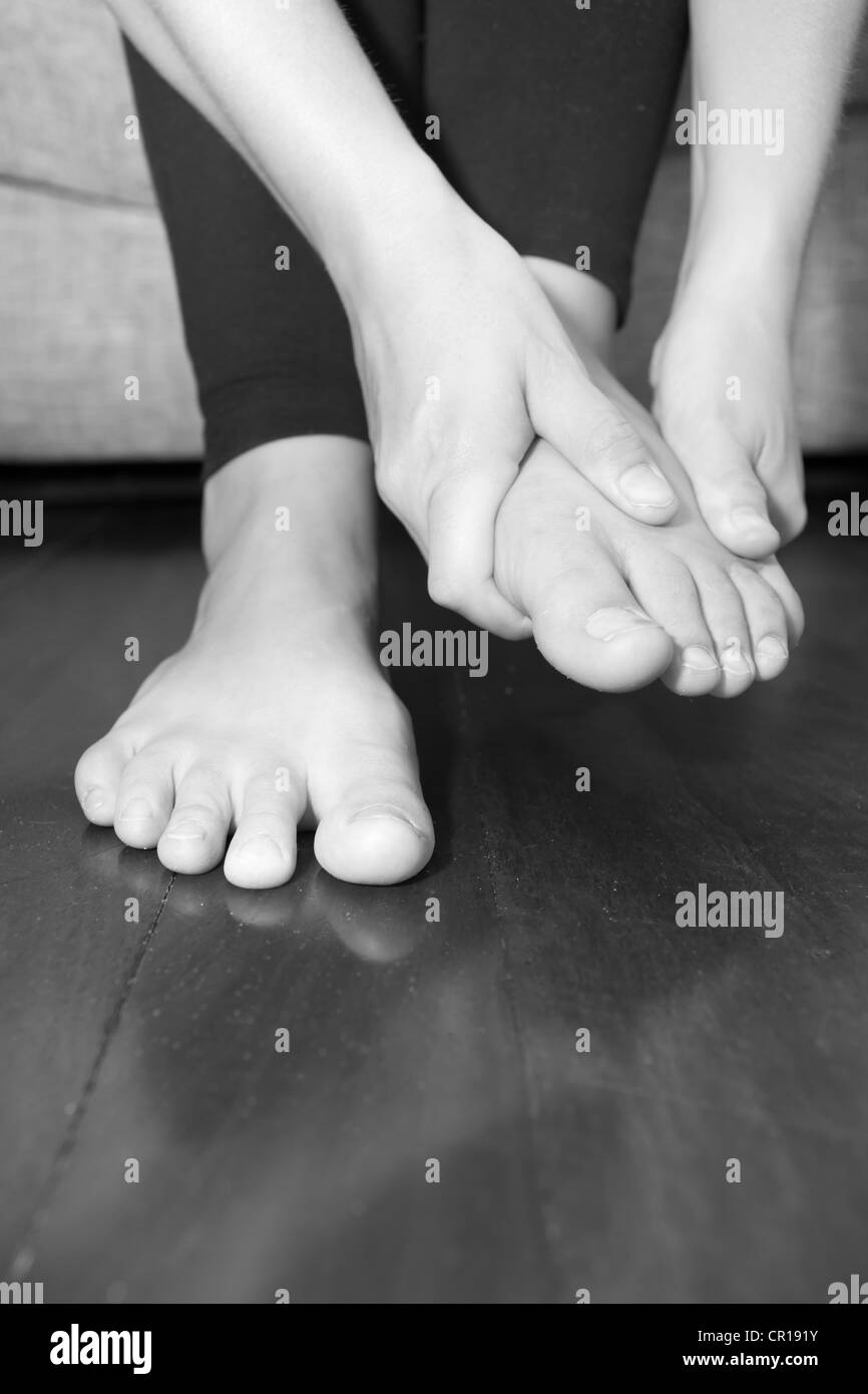 A young woman rubs her aching feet on the sofa. Stock Photo