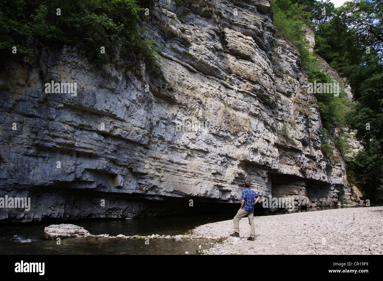 A hiker standing in front of the Amselfelsen, a huge limestone wall in the Wutach Gorge Nature Reserve, Black Forest Stock Photo