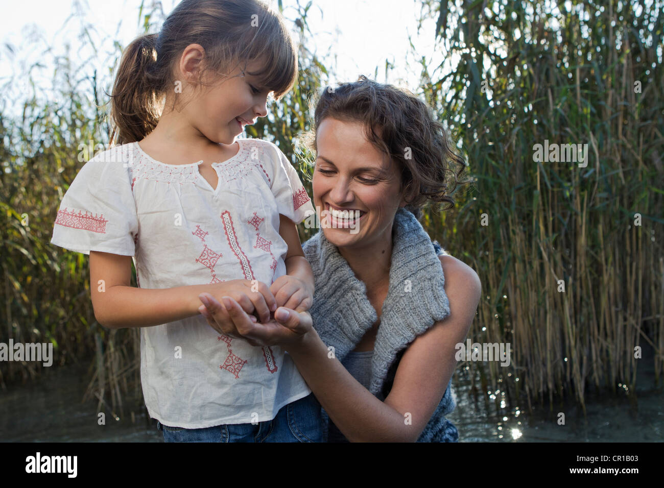 Mother and daughter talking in pond Stock Photo