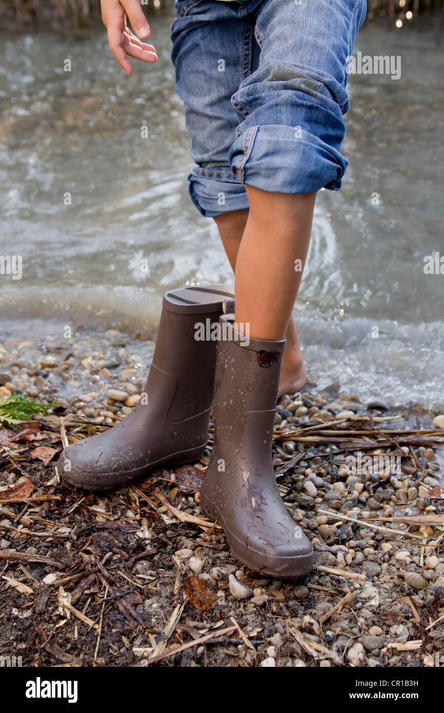 Girl taking off rain boots by pond Stock Photo - Alamy