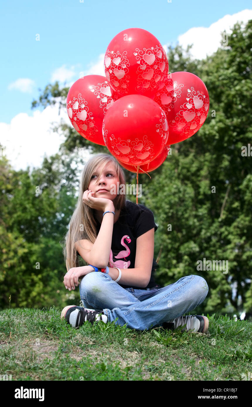 The girl - teenager sits on a grass with red balloons Stock Photo - Alamy