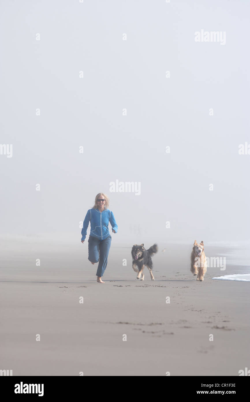 USA, California, Stinson Beach, Woman running on sandy beach in fog