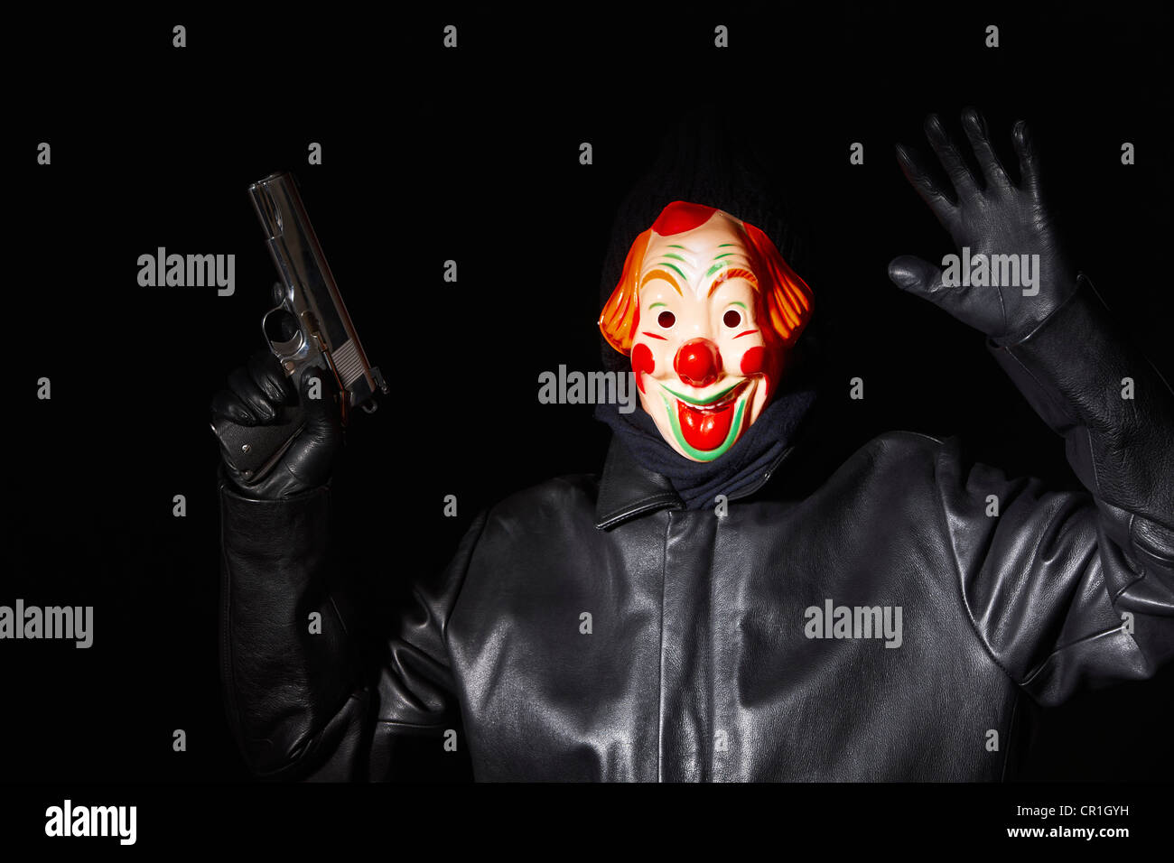Man in clown mask holding gun Stock Photo