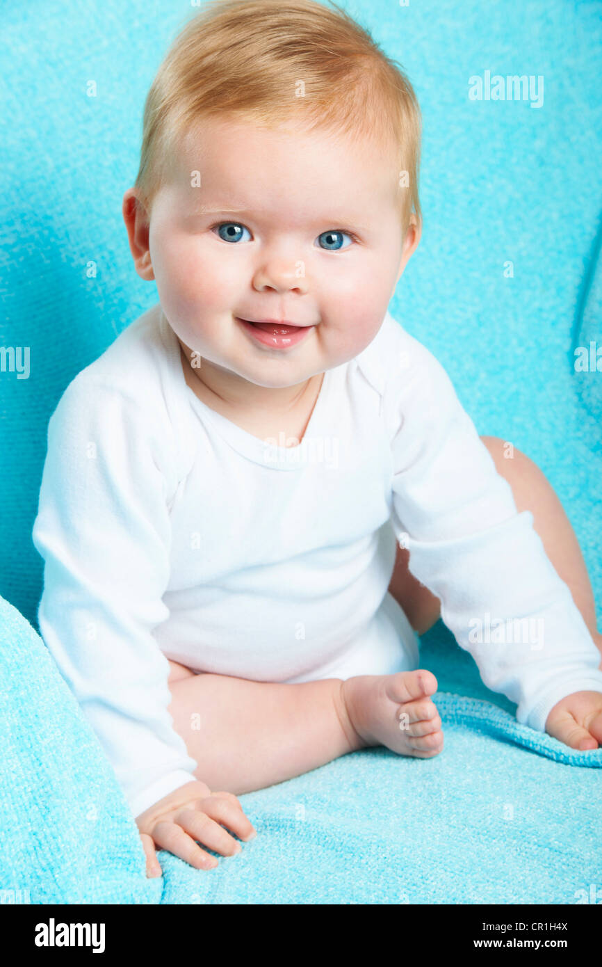 Smiling infant sitting on blue blanket Stock Photo