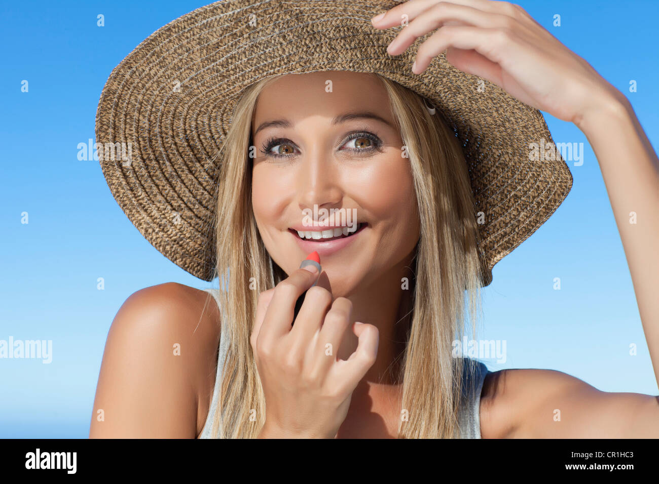 Smiling woman applying lipstick outdoors Stock Photo