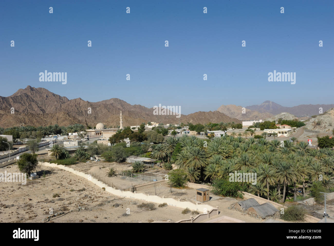 Overblick of the oasis and Arab enclave of Hatta with a mosque and palm trees, with the Hajar Mountains on the horizon Stock Photo