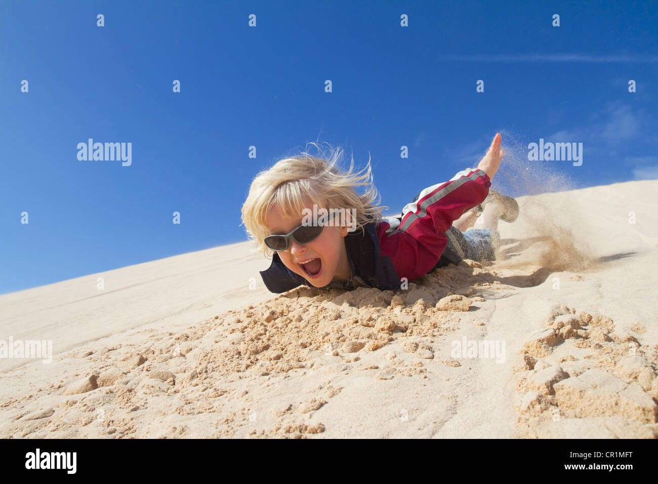 Smiling boy sliding down sand dune Stock Photo Alamy