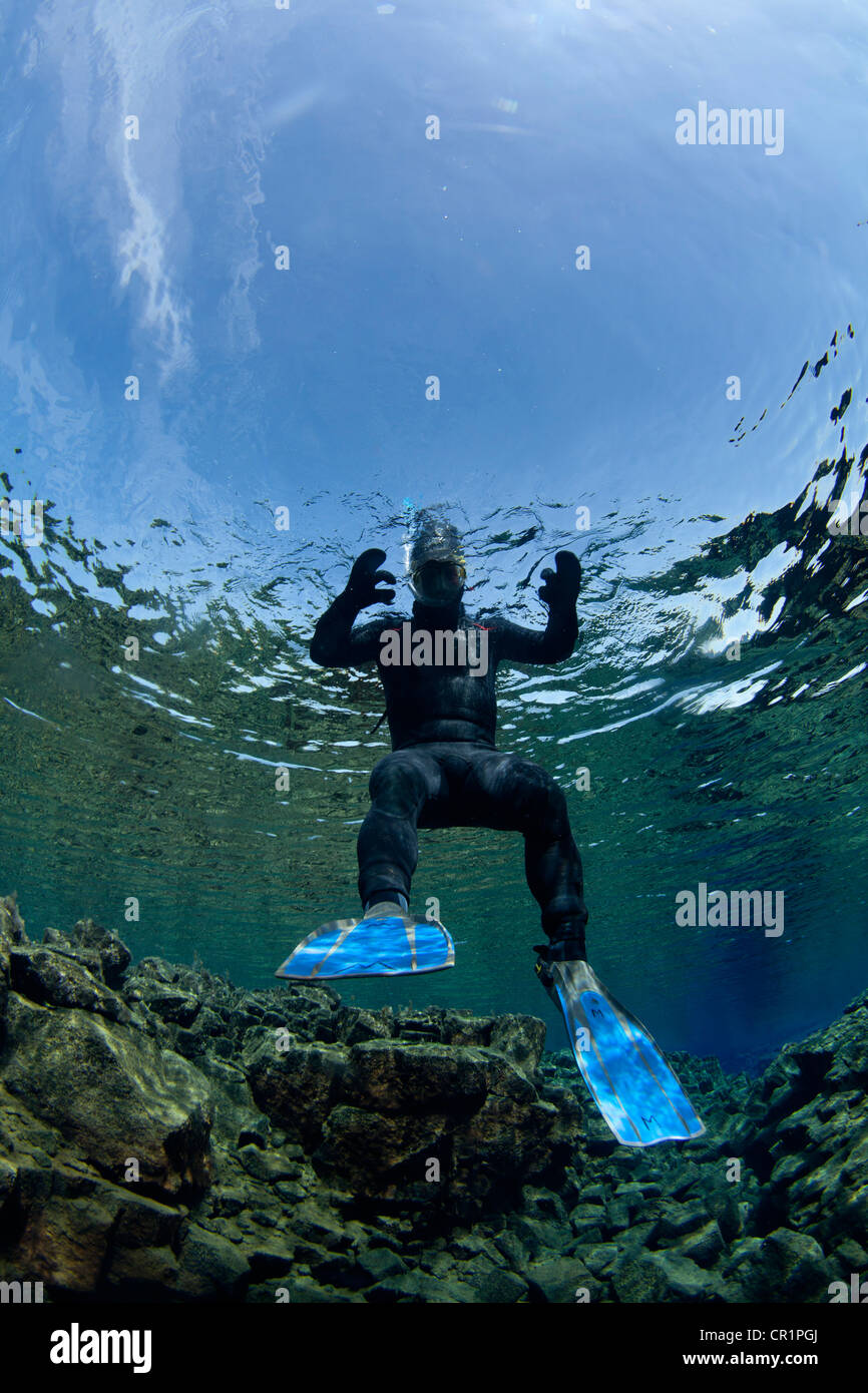 Diver swimming by rock formations Stock Photo