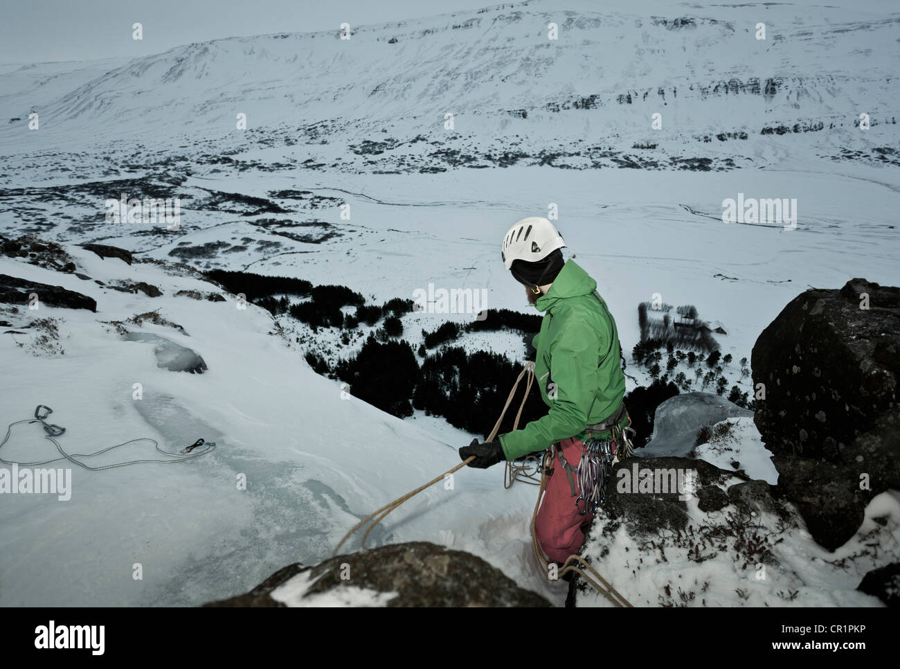 Climber with rope on snowy hill Stock Photo