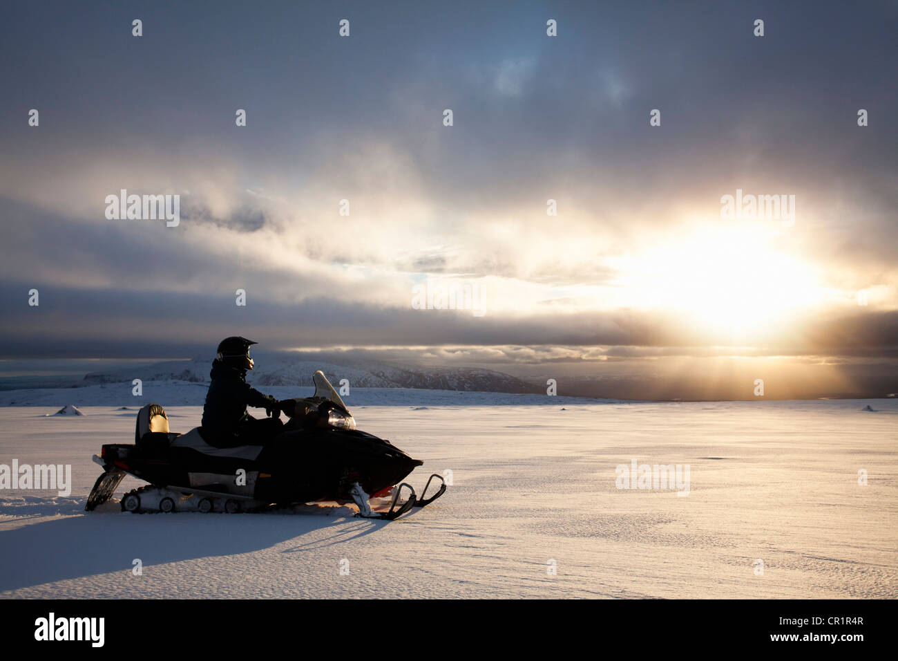 Man driving snowmobile in snowy field Stock Photo