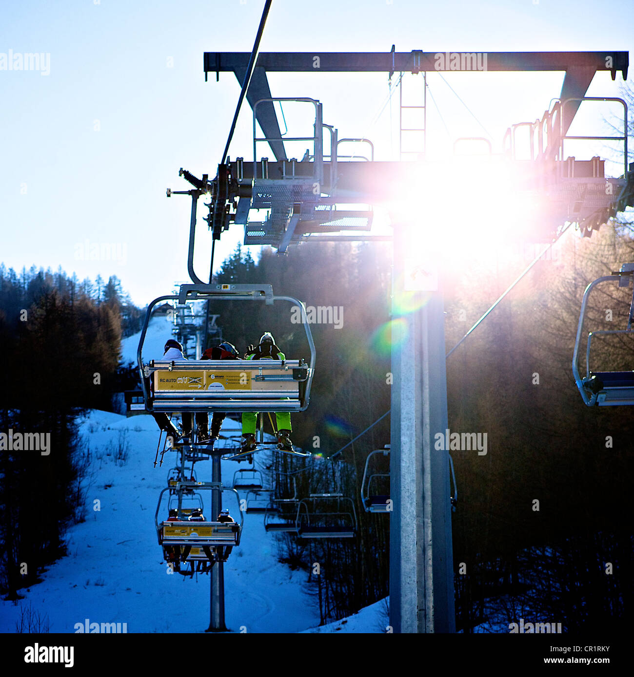 skiers on chair lift with sun glare Stock Photo