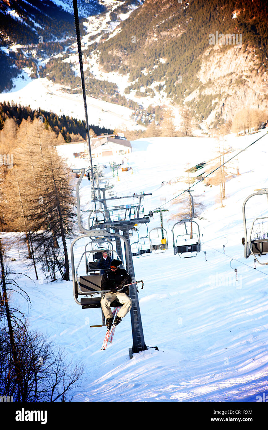 dramatic downhill view of skiers on chair lift Stock Photo