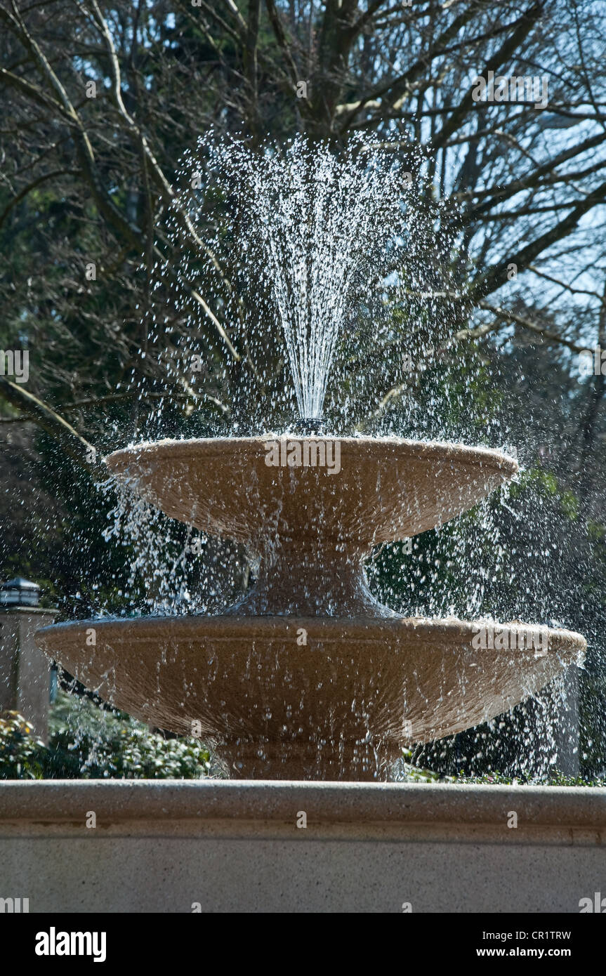 This vertical image is a water fountain with 2 tiers and the water spraying out in sunshine. Very refreshing image. Stock Photo