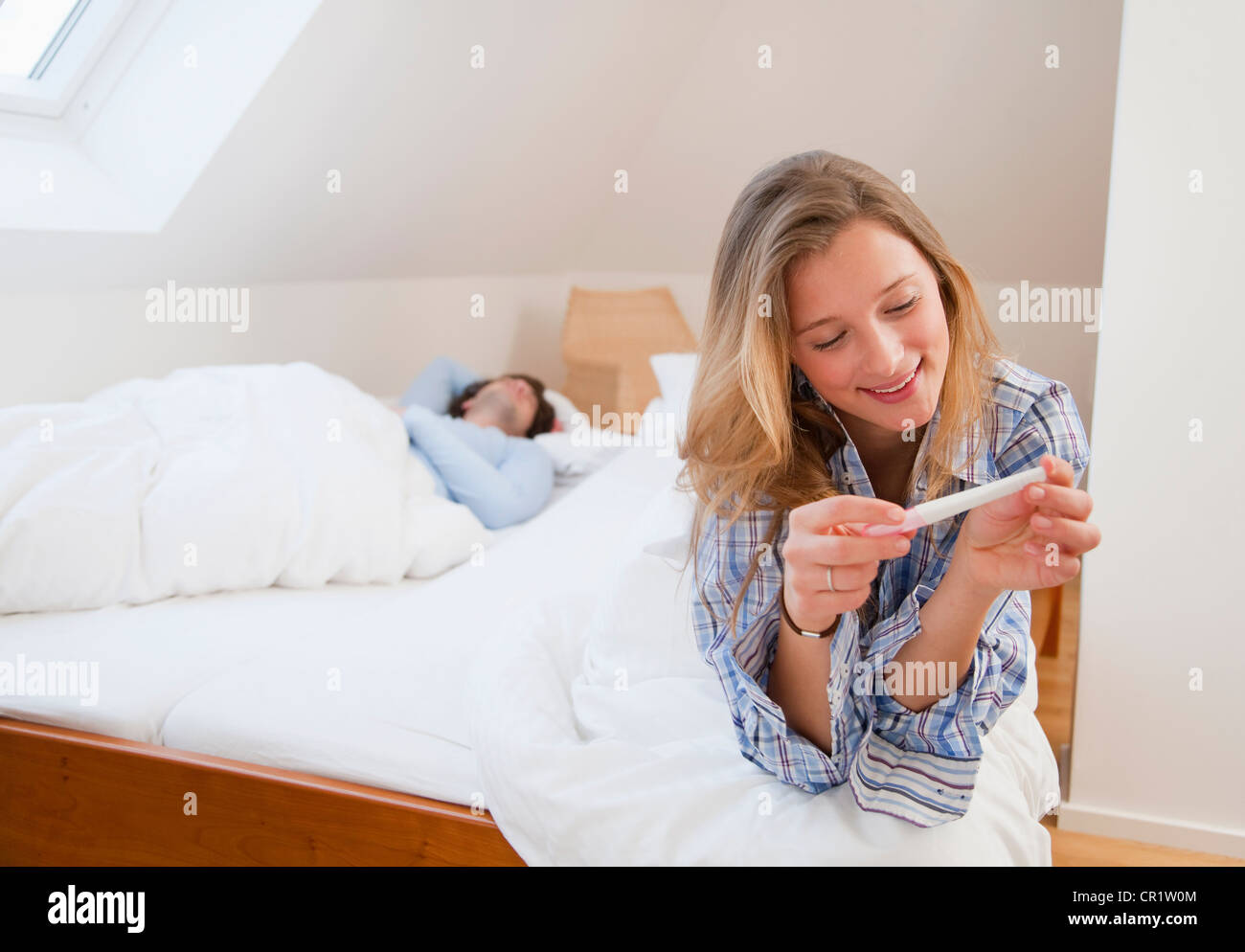 Woman reading pregnancy test on bed Stock Photo