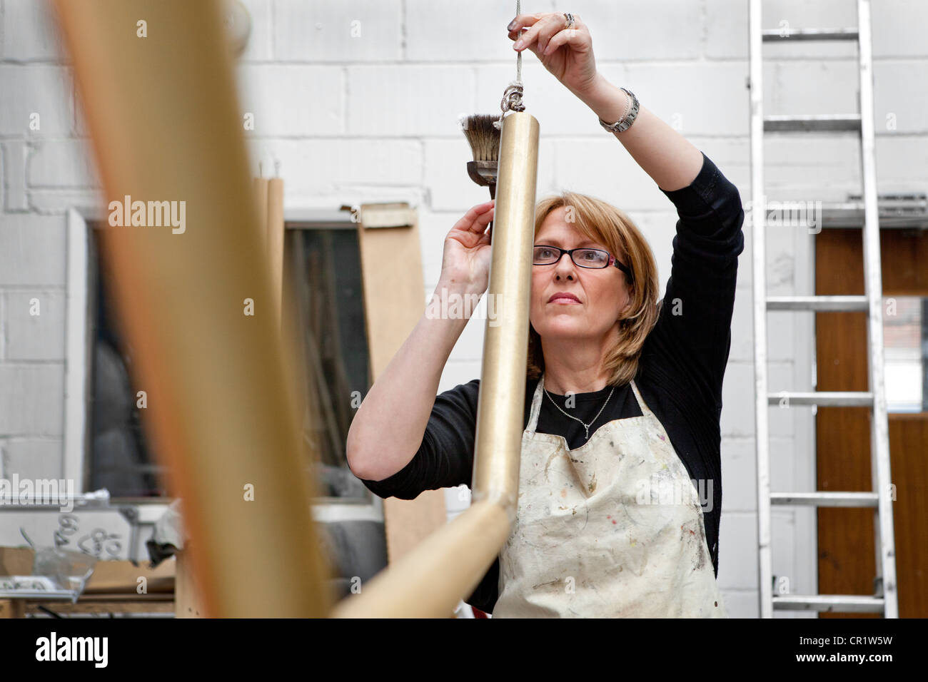 Woman doing manual labour in workshop, England Stock Photo