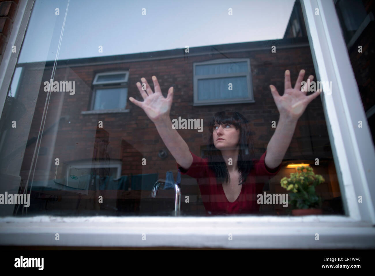 Woman in kitchen leaning on window Stock Photo