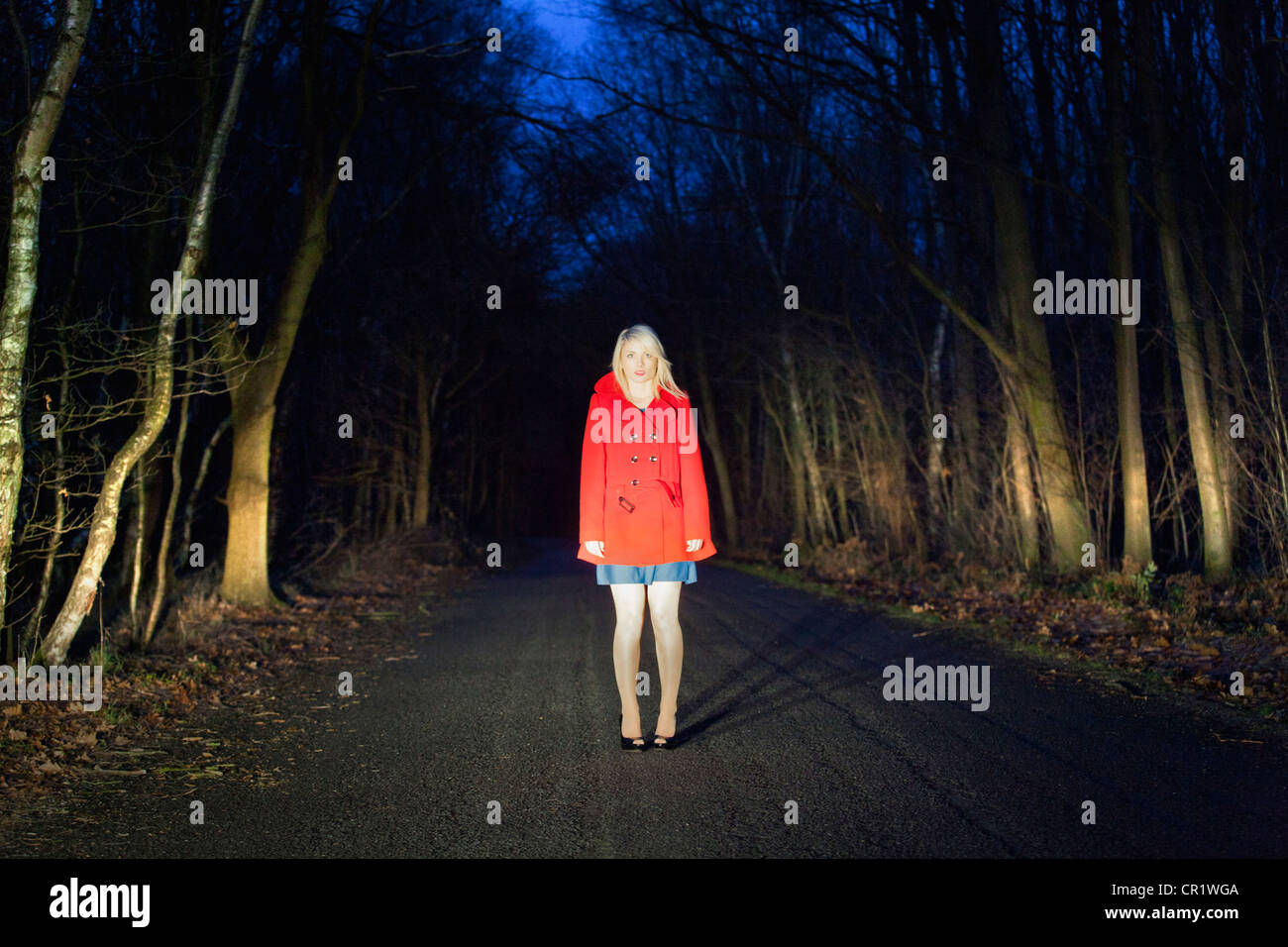 Woman standing on road in woods Stock Photo