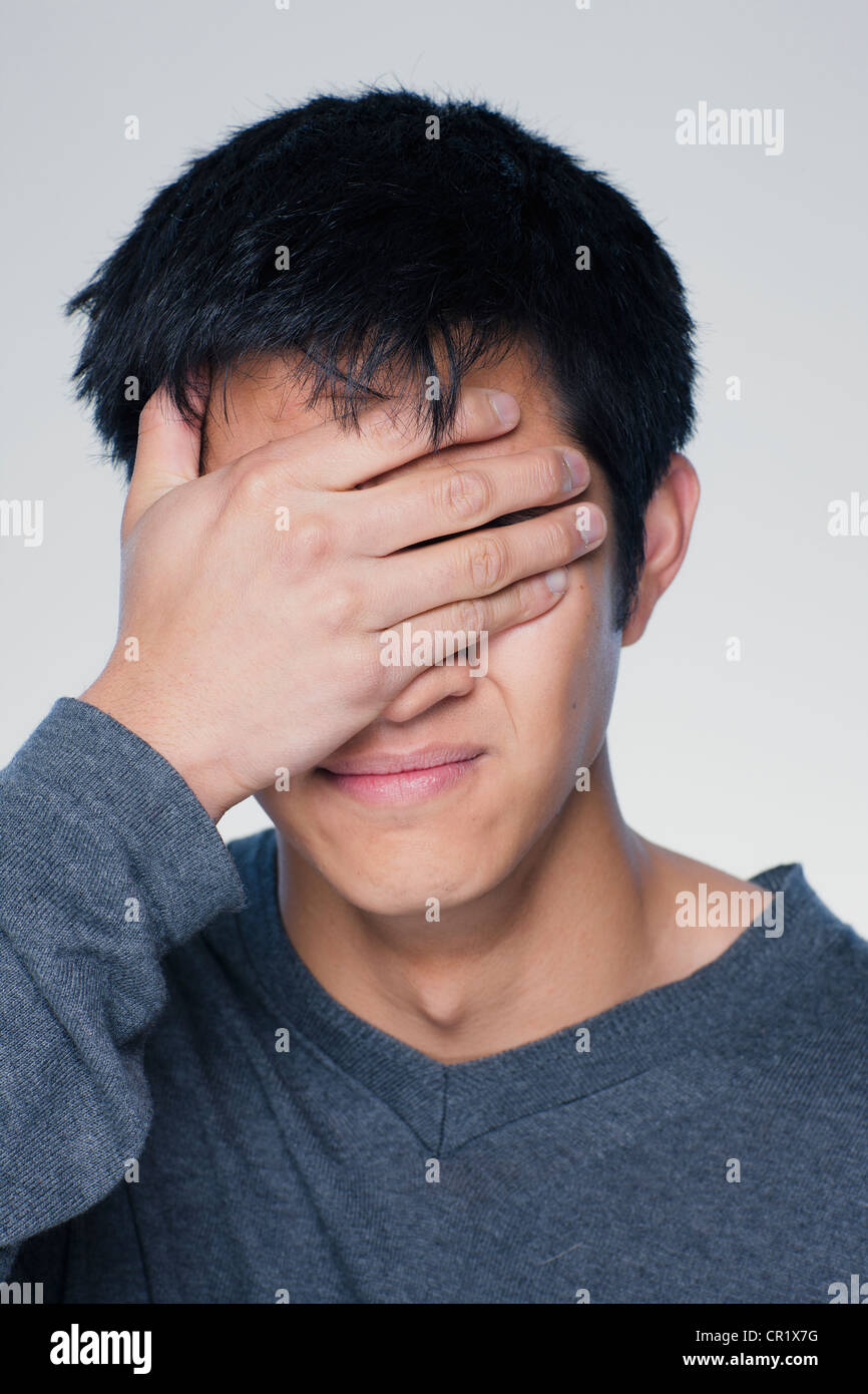 Studio portrait of young man covering eyes Stock Photo - Alamy