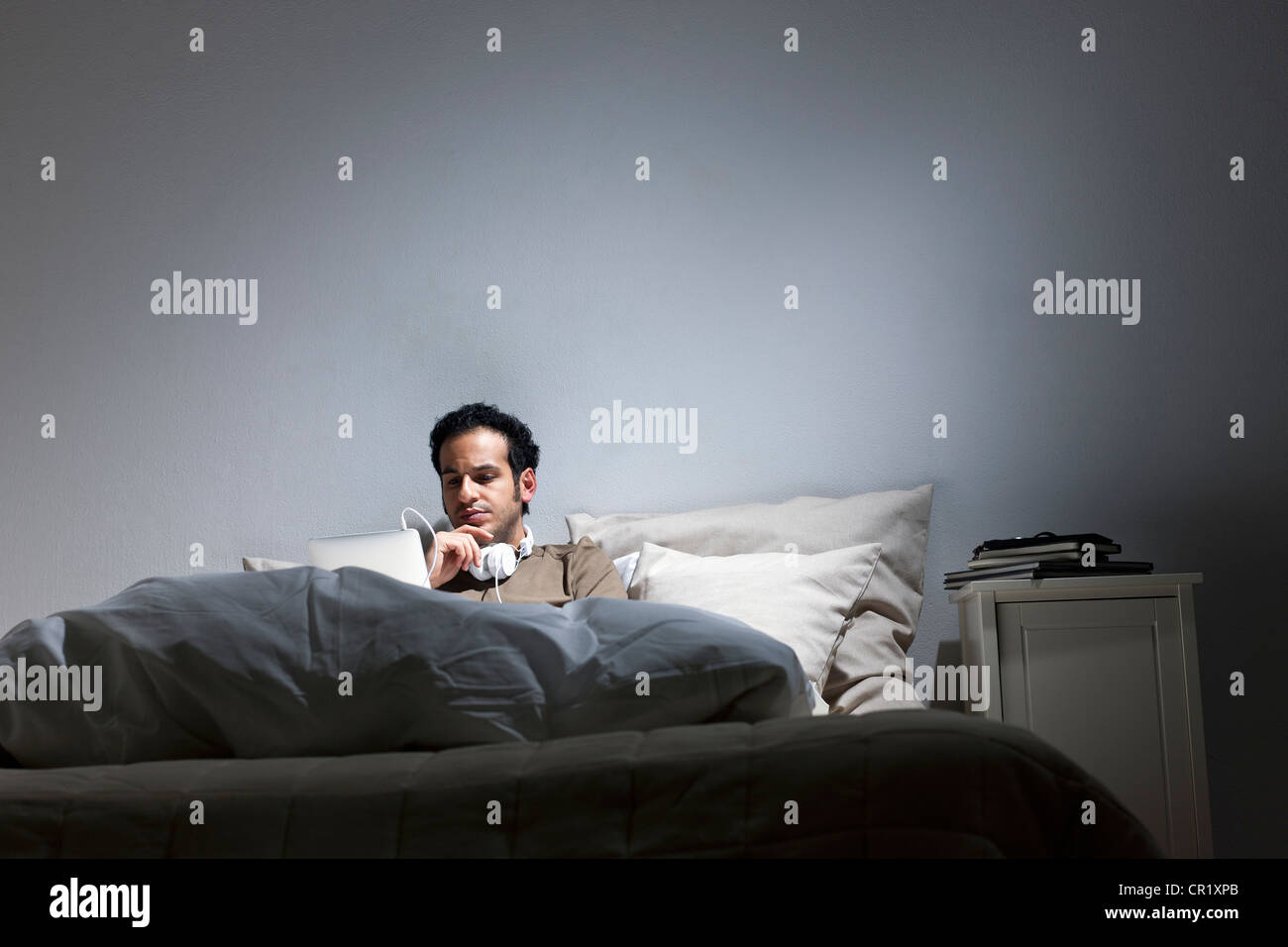 Man using tablet computer in bed Stock Photo
