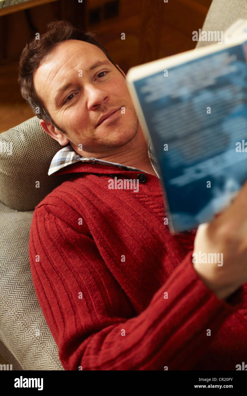 Man reading book on sofa Stock Photo