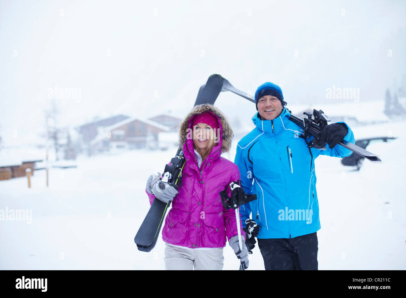 Couple carrying skis and poles in snow Stock Photo