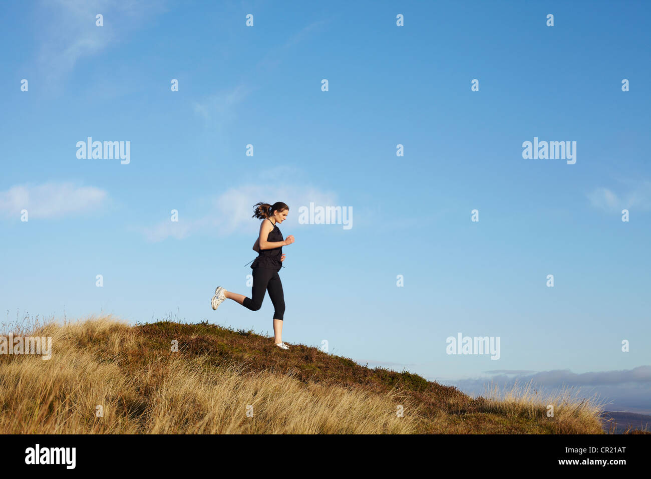Woman running on rural hillside Stock Photo