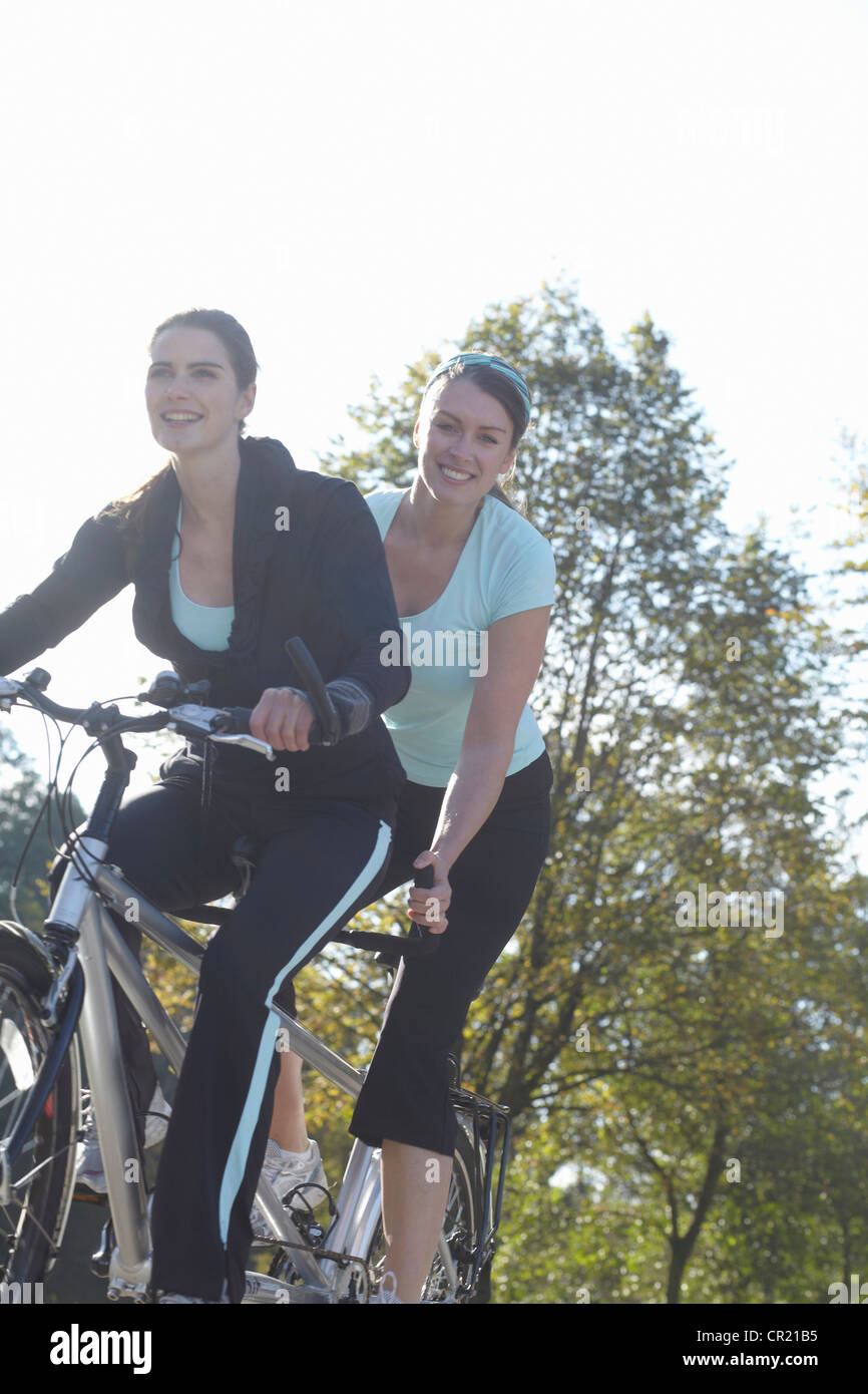 Smiling women riding tandem bicycle Stock Photo Alamy