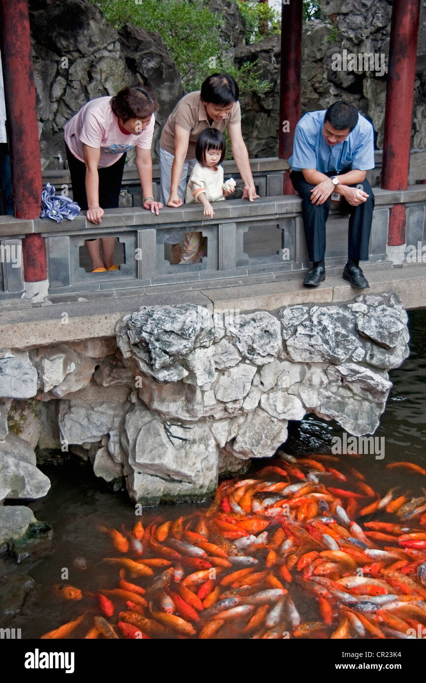 China: Girl feeding goldfish at Shanghai's Yu Yuan Garden Stock Photo