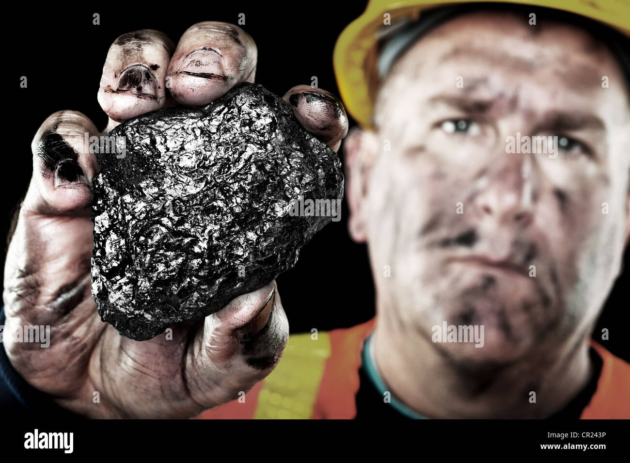 A dirty coalminer displays a lump of coal as a power and energy source. Stock Photo