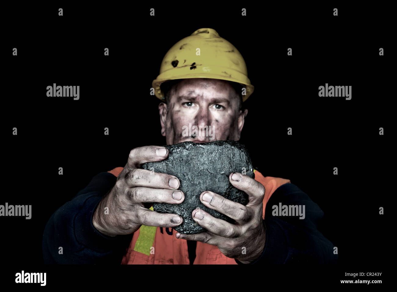 A coalminer holds out a large chunk of energy rich coal in a dark coalmine. Stock Photo