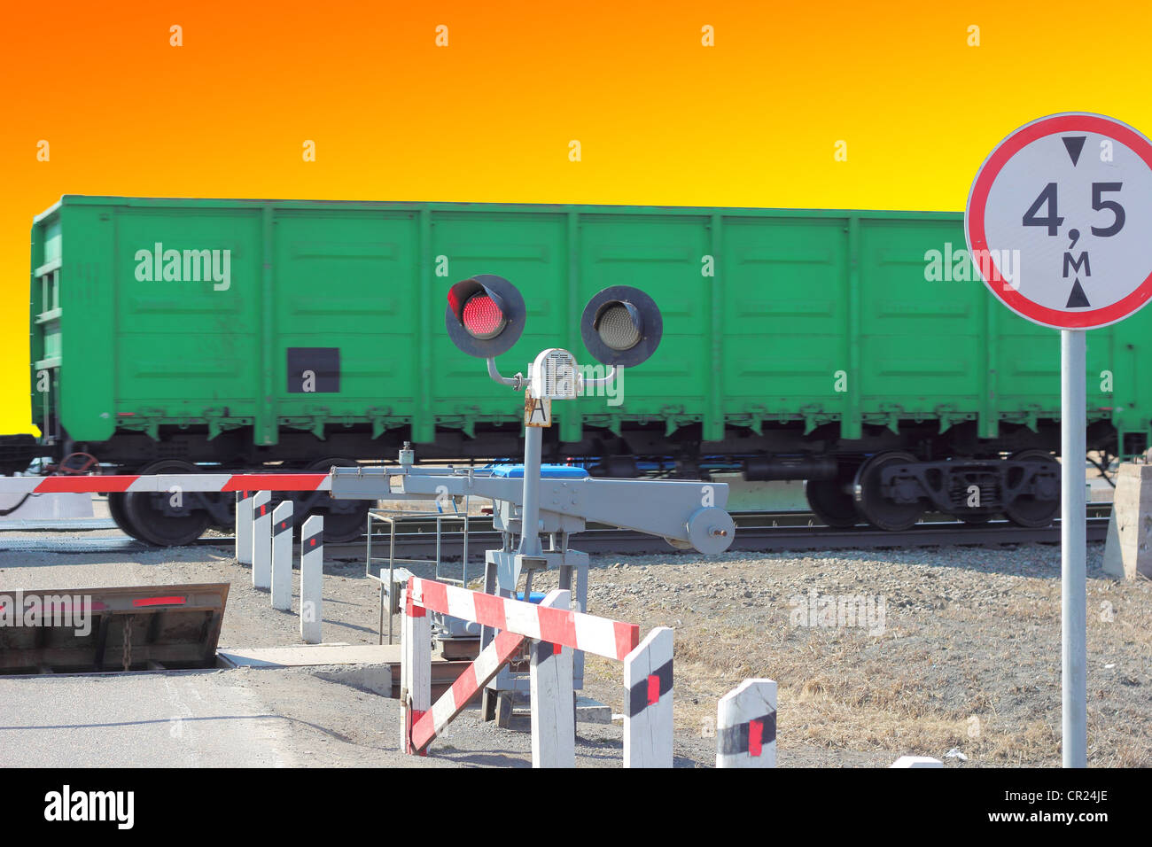 railroad cars at the crossing with a barrier and a red traffic light. Stock Photo