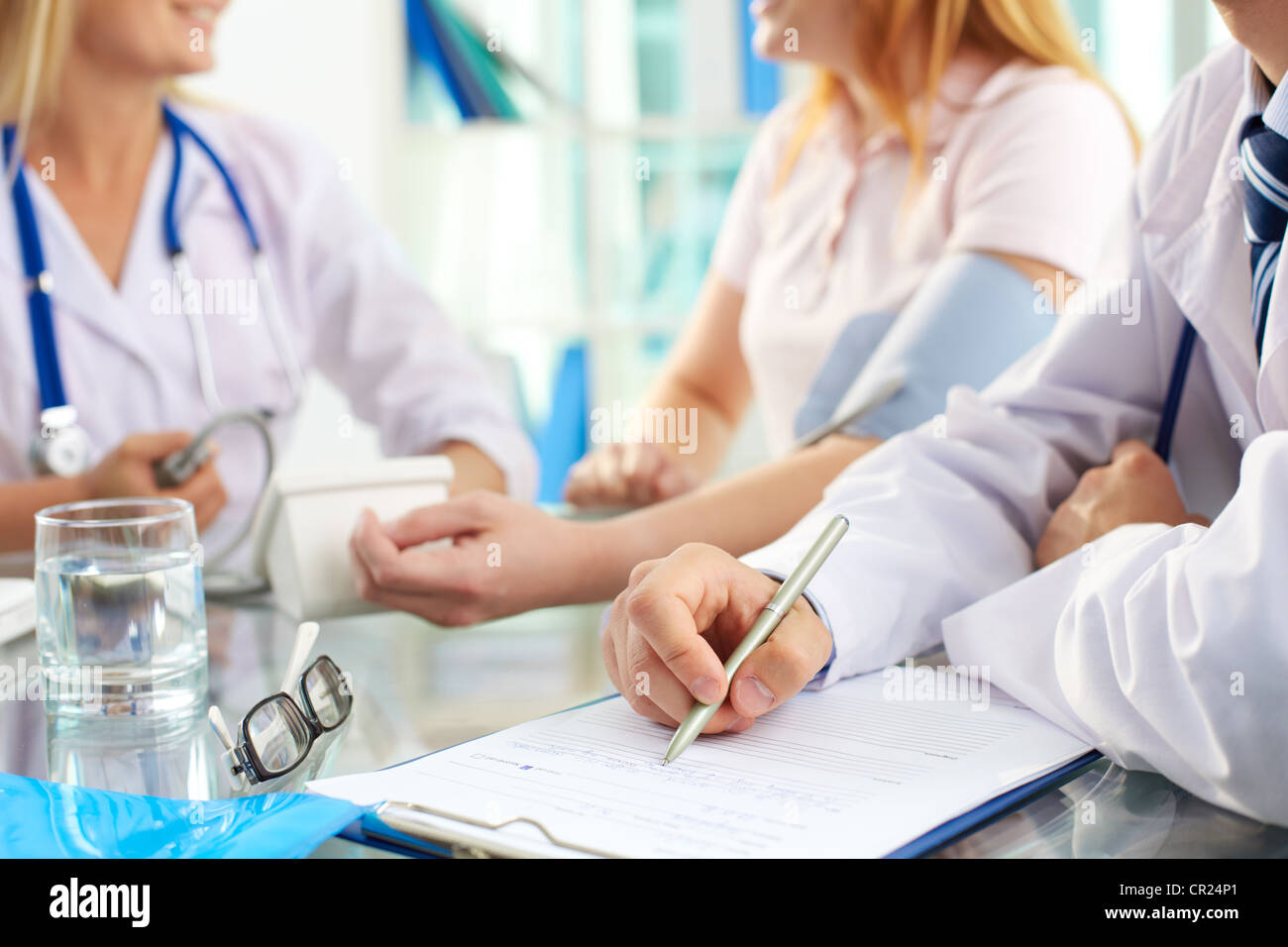 Closeup of doctor with pen writing on prescription blank at medical