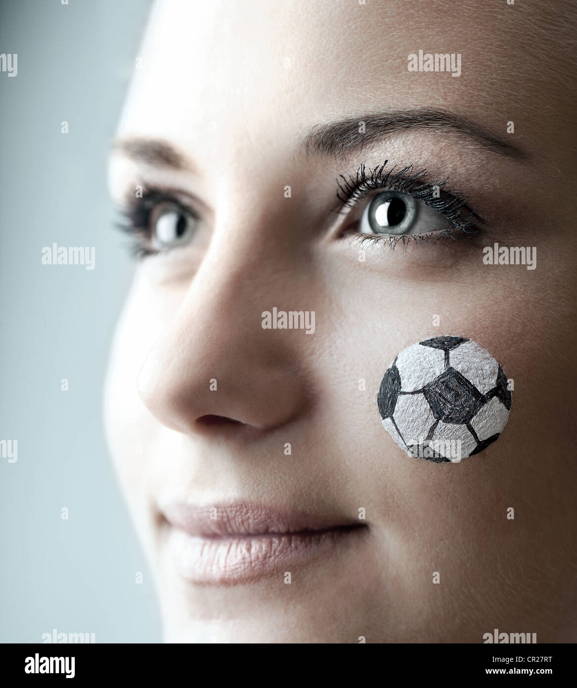 Closeup portrait of a happy football fan, painted face of a pretty woman watching ball competition, young female team supporter Stock Photo