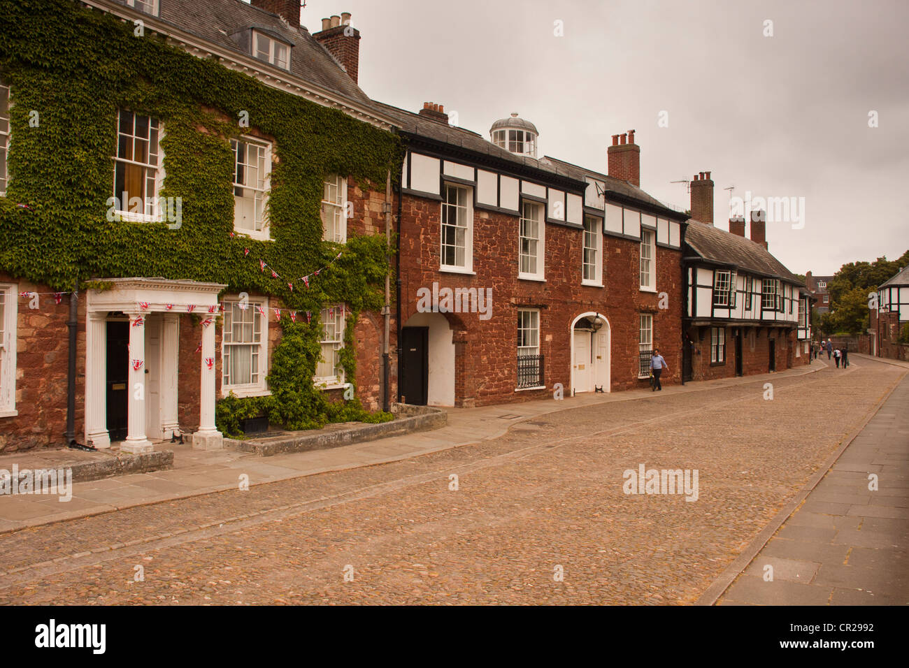 Cathedral close and cathedral yard opposite the Exeter Cathedral old houses and people having picnic lunches. Stock Photo