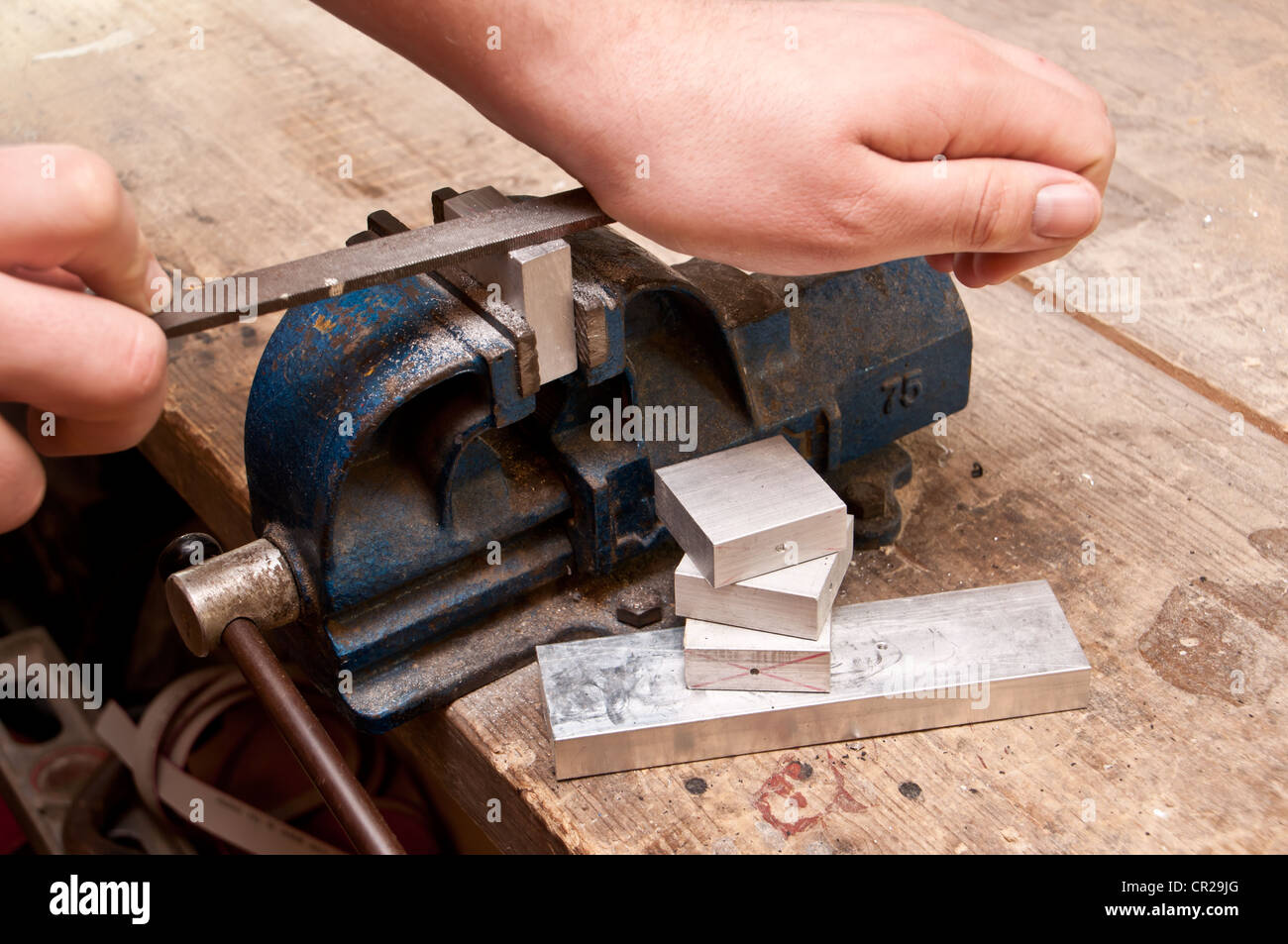 Grinding a block of metal with a file Stock Photo