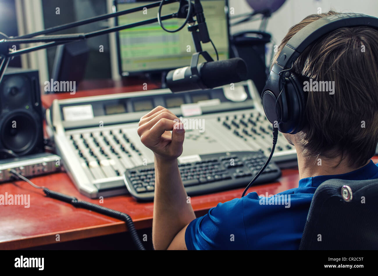 Dj working in front of a microphone on the radio, from the back Stock