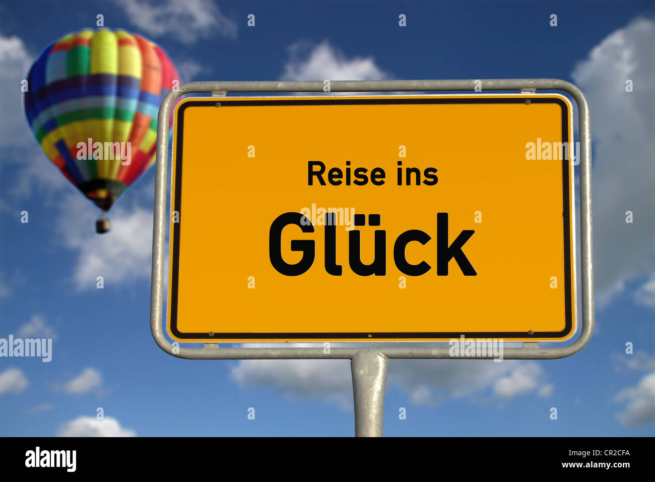 German road sign travel to happiness with captive balloon, blue sky and white clouds Stock Photo
