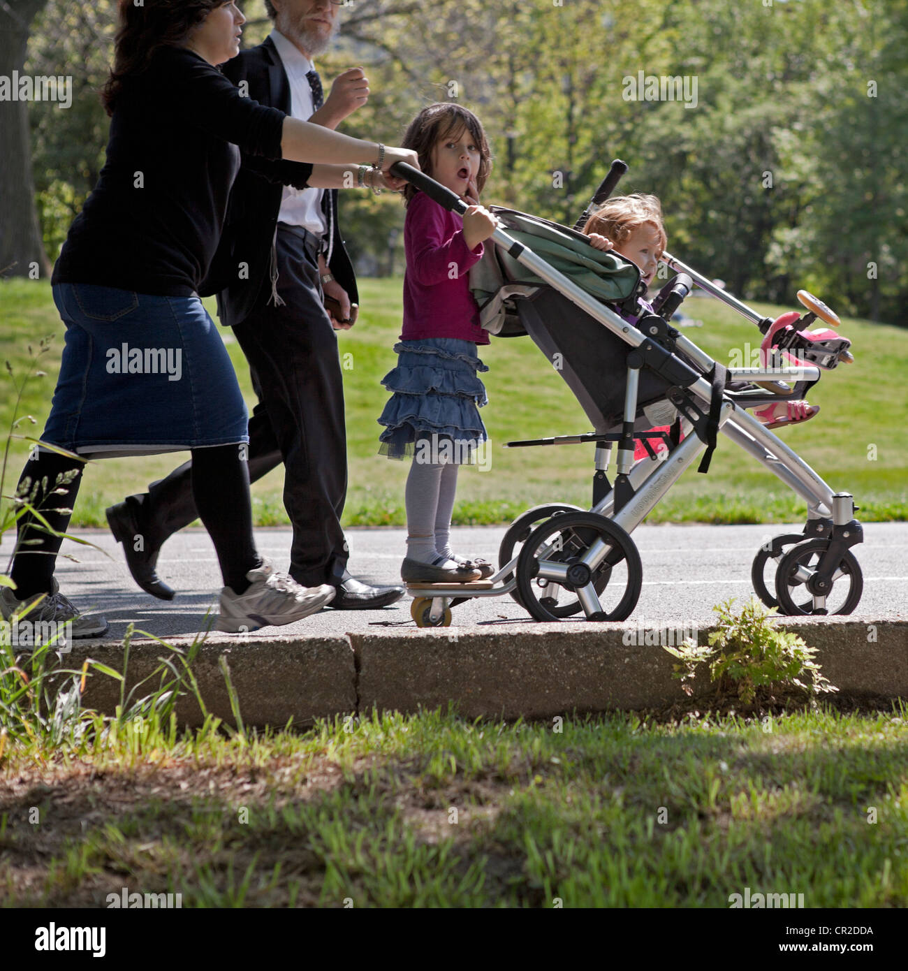 A family walks through Prospect Park in Brooklyn, New York on a sunny Sunday afternoon. Stock Photo
